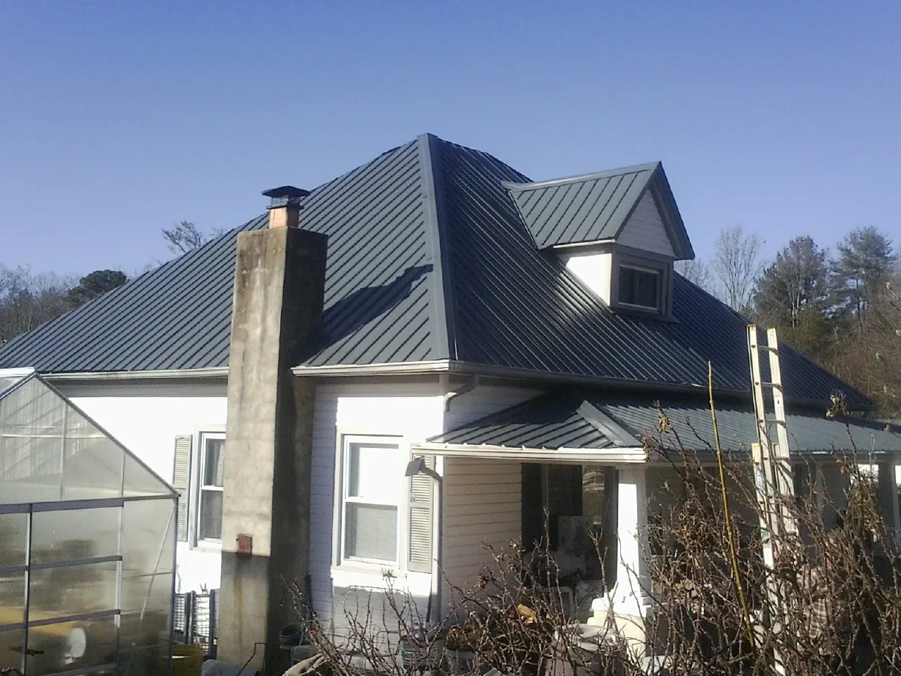 Dark blue standing seam metal roof on a white farmhouse with dormer — Slate & Tile Roof Repair by Roofing Brothers in West Terre Haute