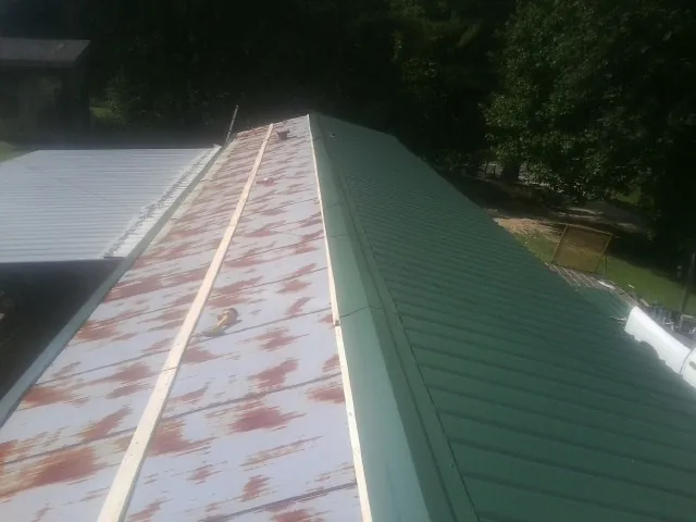 Old rusted panels beside newly installed green metal roofing — Wind Damage Roof Repair by Roofing Brothers in West Terre Haute