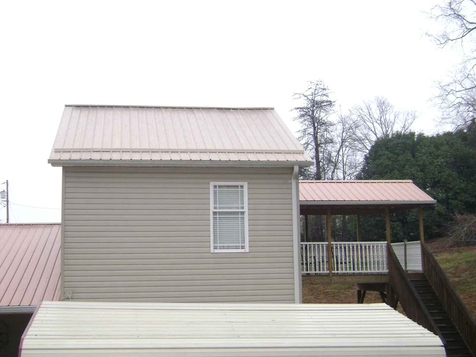 Tan metal roofs on a two story addition and attached porch, from a Roof Replacement job in West Terre Haute