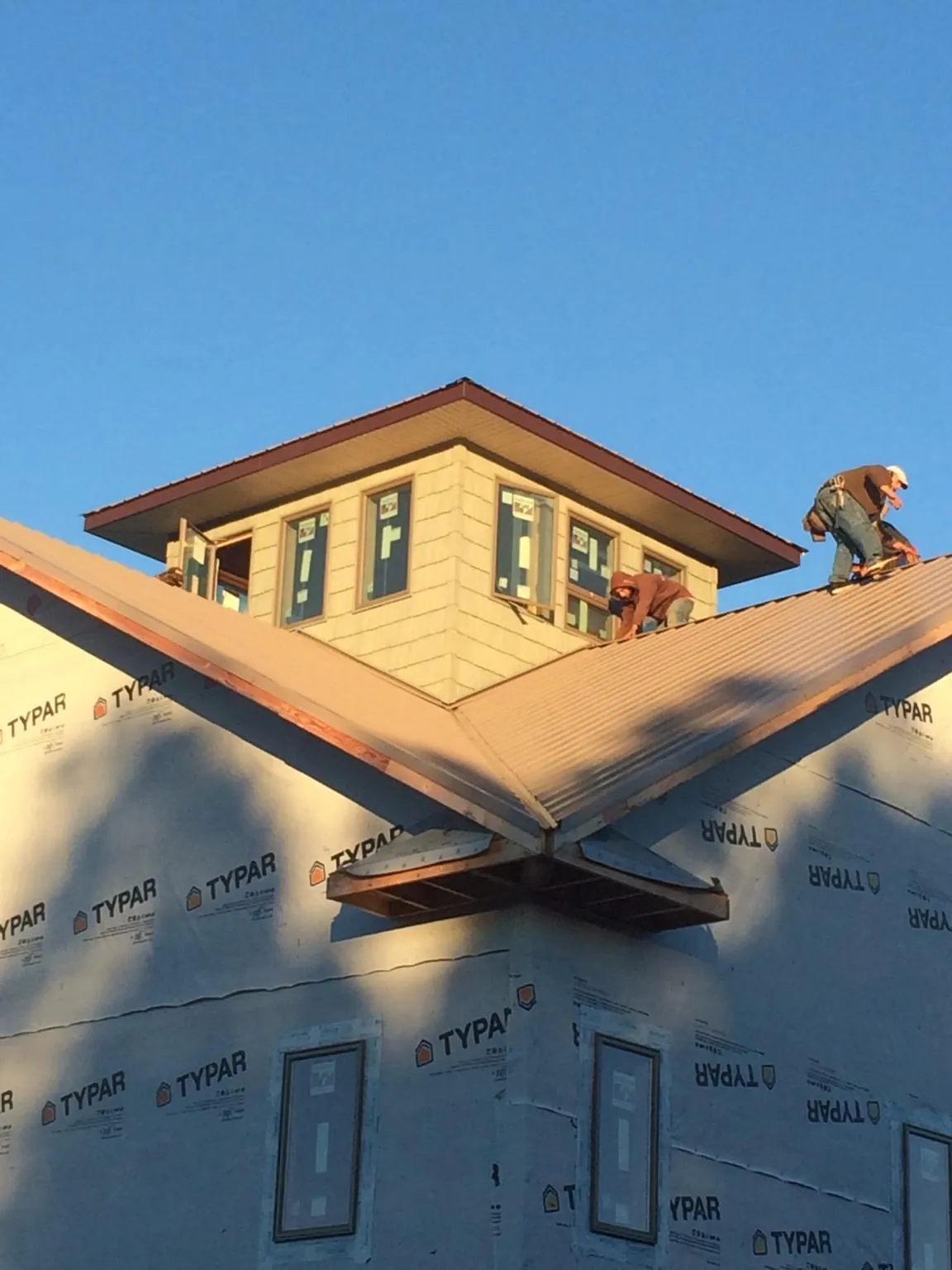 Roofers working around a rooftop cupola on a new metal roof at sunset — Roof Waterproofing in West Terre Haute by Roofing Brothers